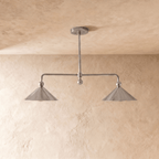 Clérachic chandelier in chrome, softly lit view of the paired cone shades and slender ceiling rod.