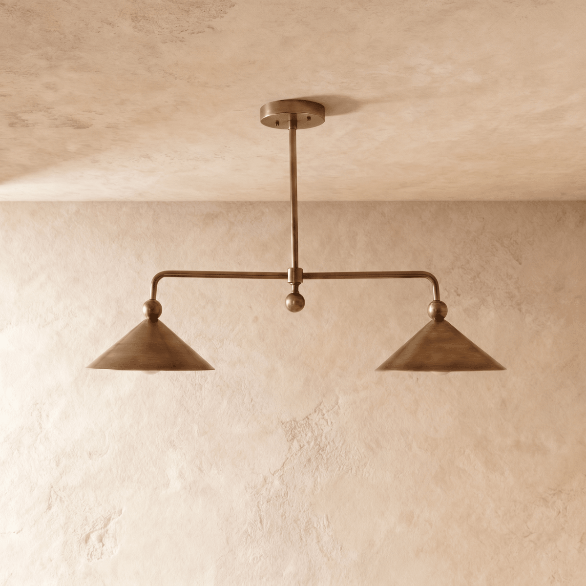Clérachic chandelier in vintage brass, front view of the paired cone shades on their angled ceiling bar.