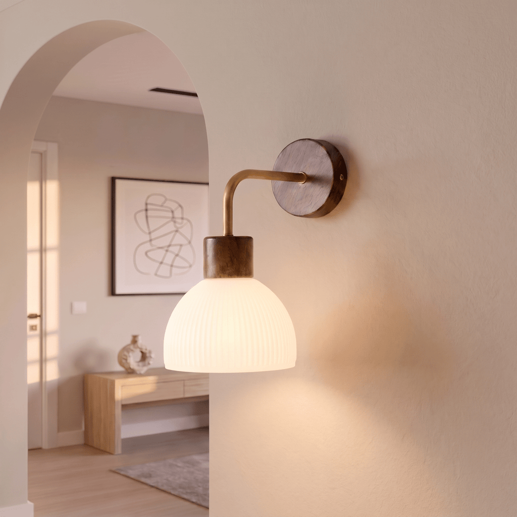 This Clérachic wall light glows softly beside an archway, its ribbed glass dome lighting a console table beyond.