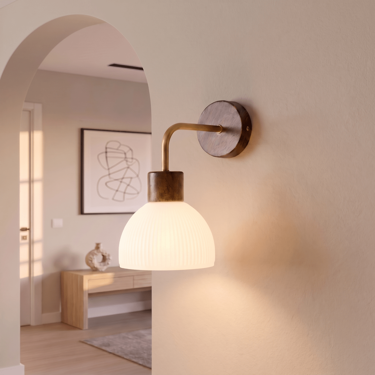 This Clérachic wall light glows softly beside an archway, its ribbed glass dome lighting a console table beyond.