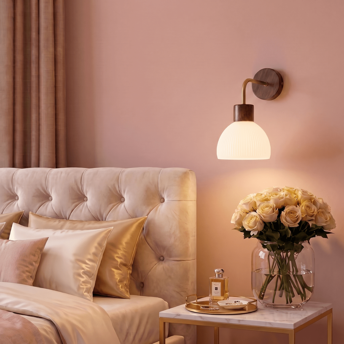 A Clérachic wall light glows beside a tufted headboard, lighting a marble nightstand with a rose bouquet.
