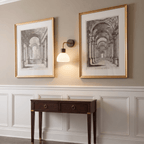 This Clérachic wall light glows between two framed architectural prints above a dark wood console table.