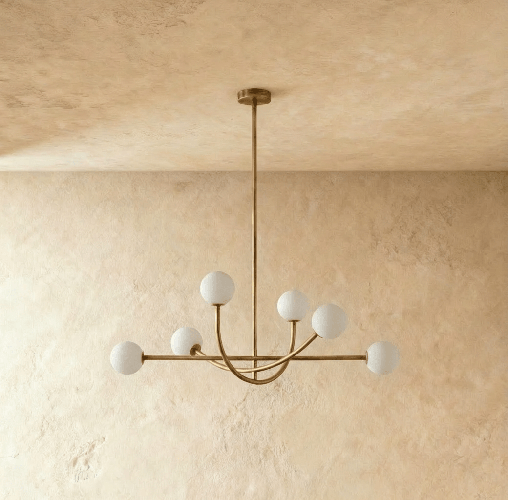 Clérachic six-globe chandelier in a brass-toned finish, unlit, the downrod dropping from a round ceiling canopy to the crossing arms below.