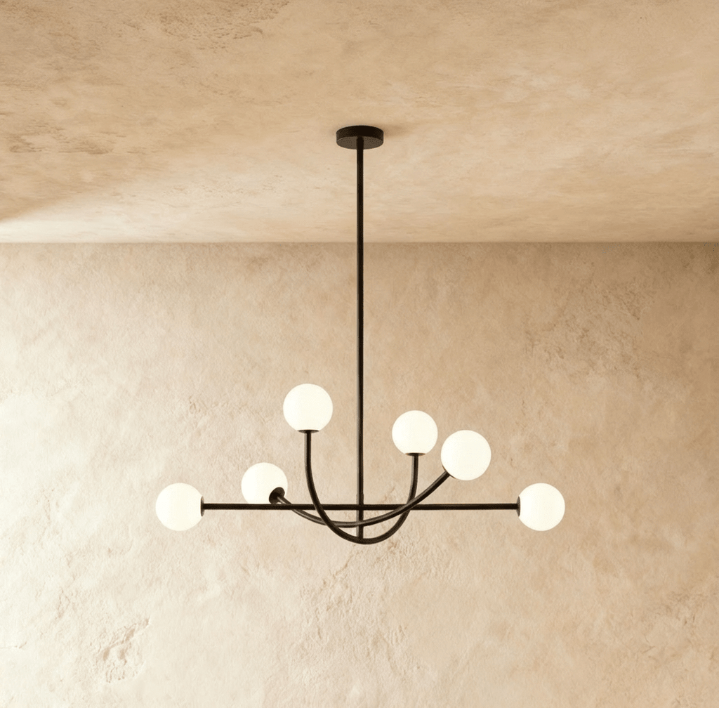 Clérachic six-globe chandelier in a matte black finish, its globes glowing warm white against a plain plaster wall.