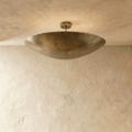 Clérachic ceiling light in vintage brass, its boat-shaped bowl shade mounted flush below a plaster ceiling.