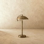 Clérachic dome table lamp in vintage brass, its shade reaching past the round base on both sides.