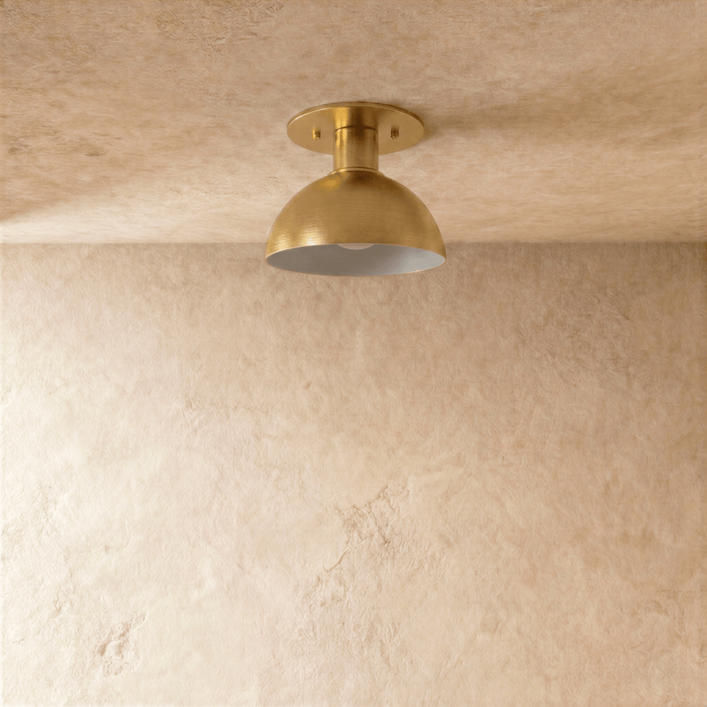 Clérachic ceiling light in satin brass, front-on view of the dome shade glowing from within.