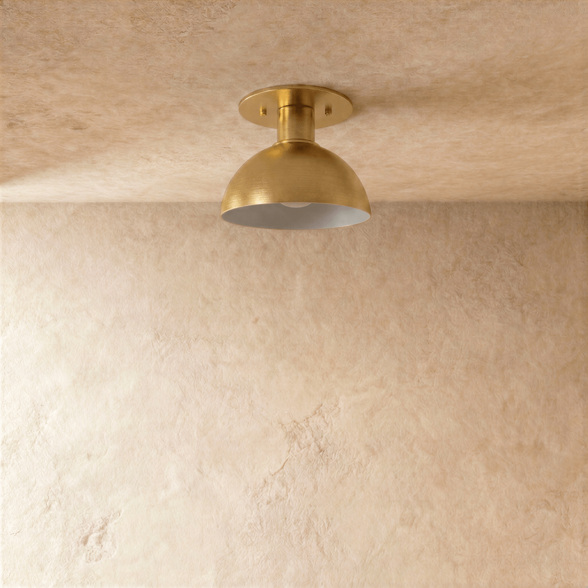 Clérachic ceiling light in satin brass, front-on view of the dome shade glowing from within.