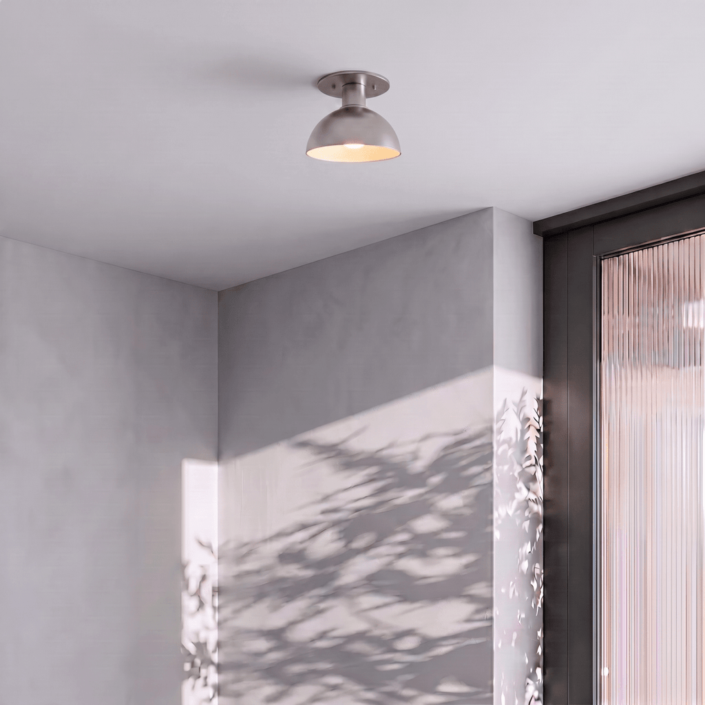 Clérachic ceiling light in chrome mounted in a grey hallway with dappled plant-shadow on the wall.