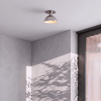 Clérachic ceiling light in chrome mounted in a grey hallway with dappled plant-shadow on the wall.