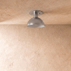Clérachic ceiling light in chrome, front-on view of the rounded dome shade glowing softly from within.