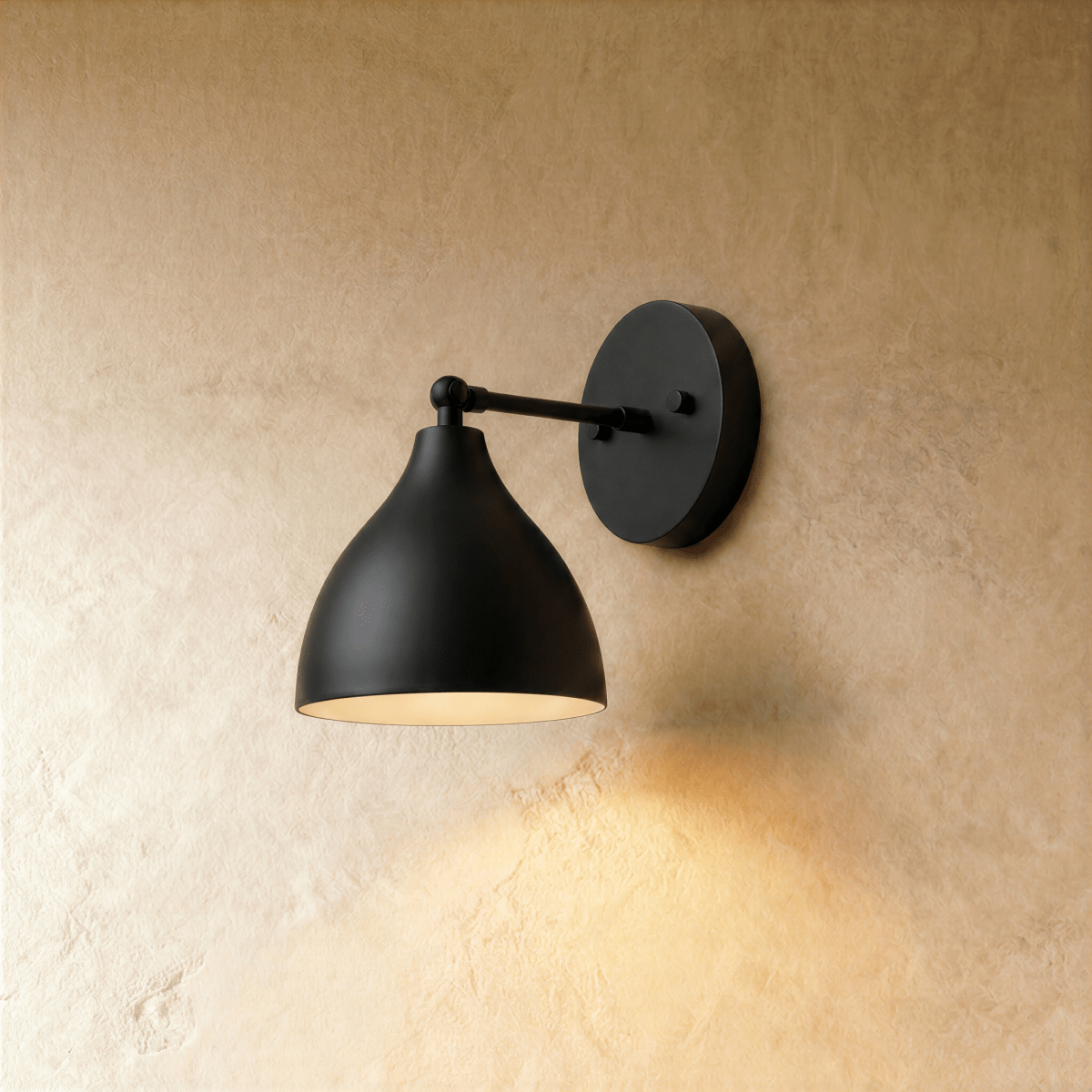 A matte black Clérachic wall lamp with a bell-shaped shade on a straight arm against a plaster wall.