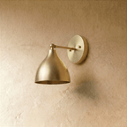 This vintage brass Clérachic wall lamp is shown from another angle, its bell shade tilted toward the light.