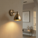 This vintage brass Clérachic wall lamp lights a hallway arch leading to a console table and framed art.