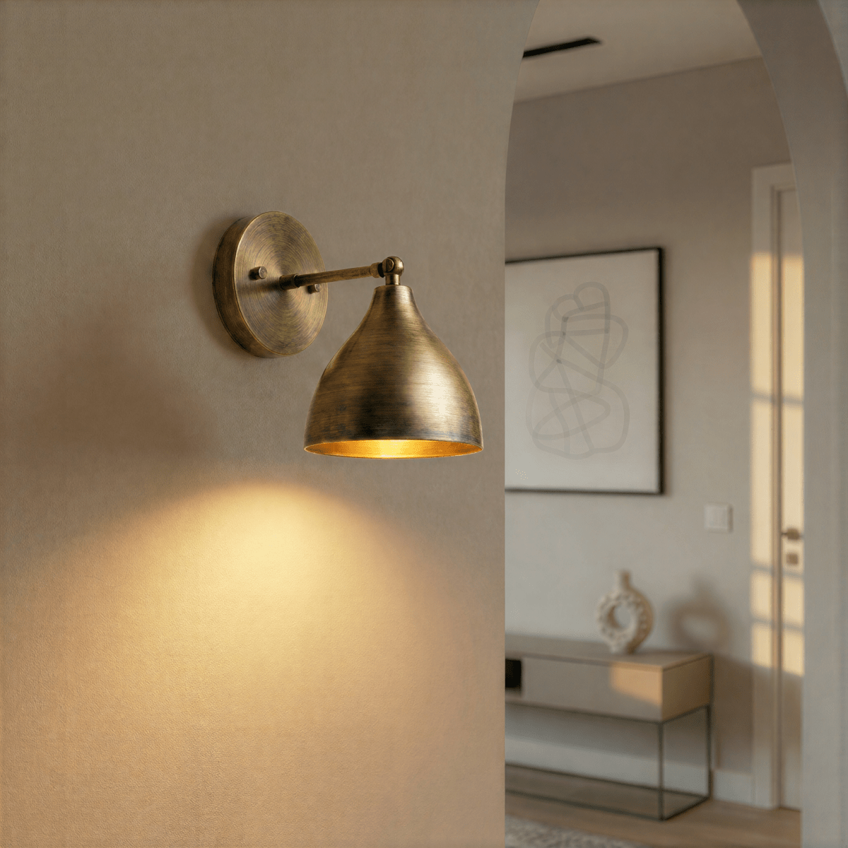 This vintage brass Clérachic wall lamp lights a hallway arch leading to a console table and framed art.