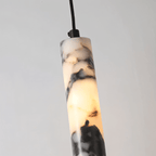 Clérachic marble pendant light in close-up, showing the black collar that caps the stone column where the cord enters.