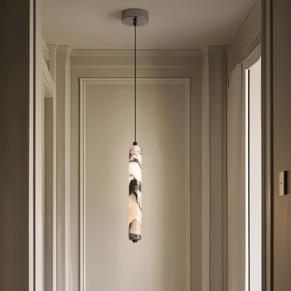 Clérachic marble pendant light lit in a panelled hallway, its cord dropping from a pale grey ceiling canopy.