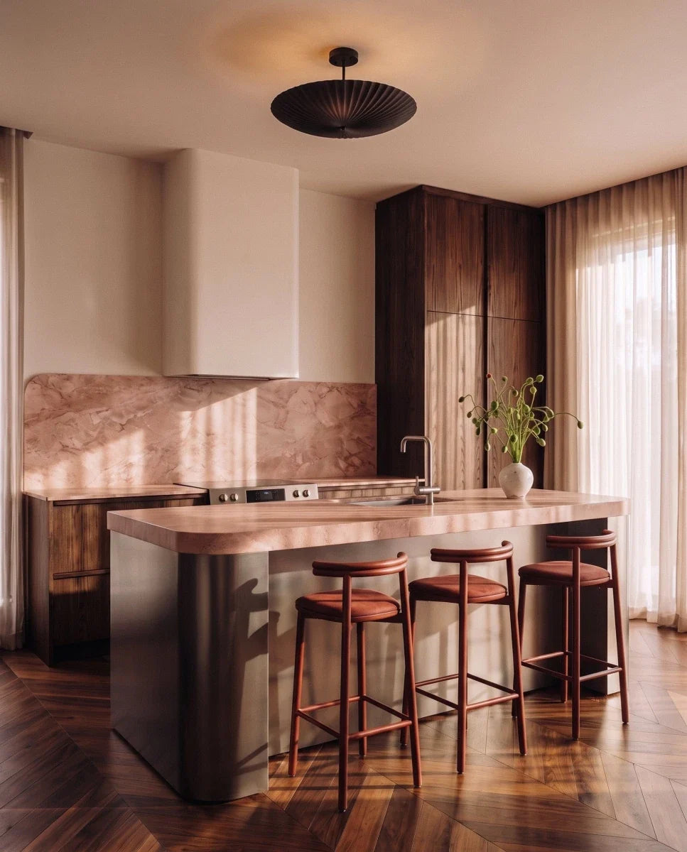 Clérachic pendant light in matte black hung above a kitchen island with pink marble and walnut cabinetry.