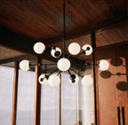 Clérachic chandelier in matte black hanging beneath a timber ceiling beside tall window panes.