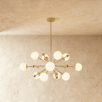 Clérachic chandelier in brushed brass, a sputnik burst of opal glass globes on slender arms.