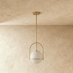 Clérachic globe pendant light in brass-tone gold, hanging from a rigid stem below a round, flat ceiling canopy.