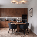 Clérachic ceiling light glowing above a round dining table in a walnut kitchen with dark chairs.