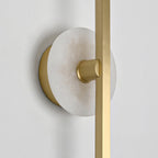 Close-up of a Clérachic wall sconce's alabaster disc and brass mounting point, photographed against a plain wall.