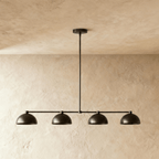 Clérachic four-dome bar pendant light in black, unlit, its slim rod running up to a shallow round canopy at the ceiling.