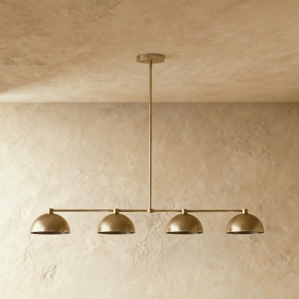 Clérachic four-dome bar pendant light in aged brass, switched off, showing the short collar that caps each dome where it meets the bar.