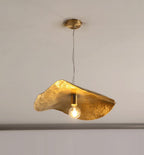 This Clérachic pendant hangs lit from a round brass ceiling mount in a bare studio setting.