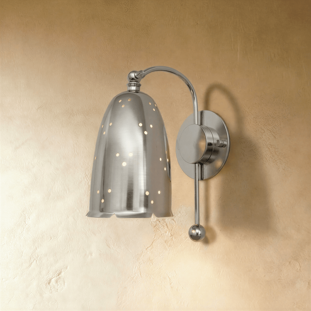 Clérachic wall lamp in chrome, its perforated bell shade suspended from a curved metal arm.