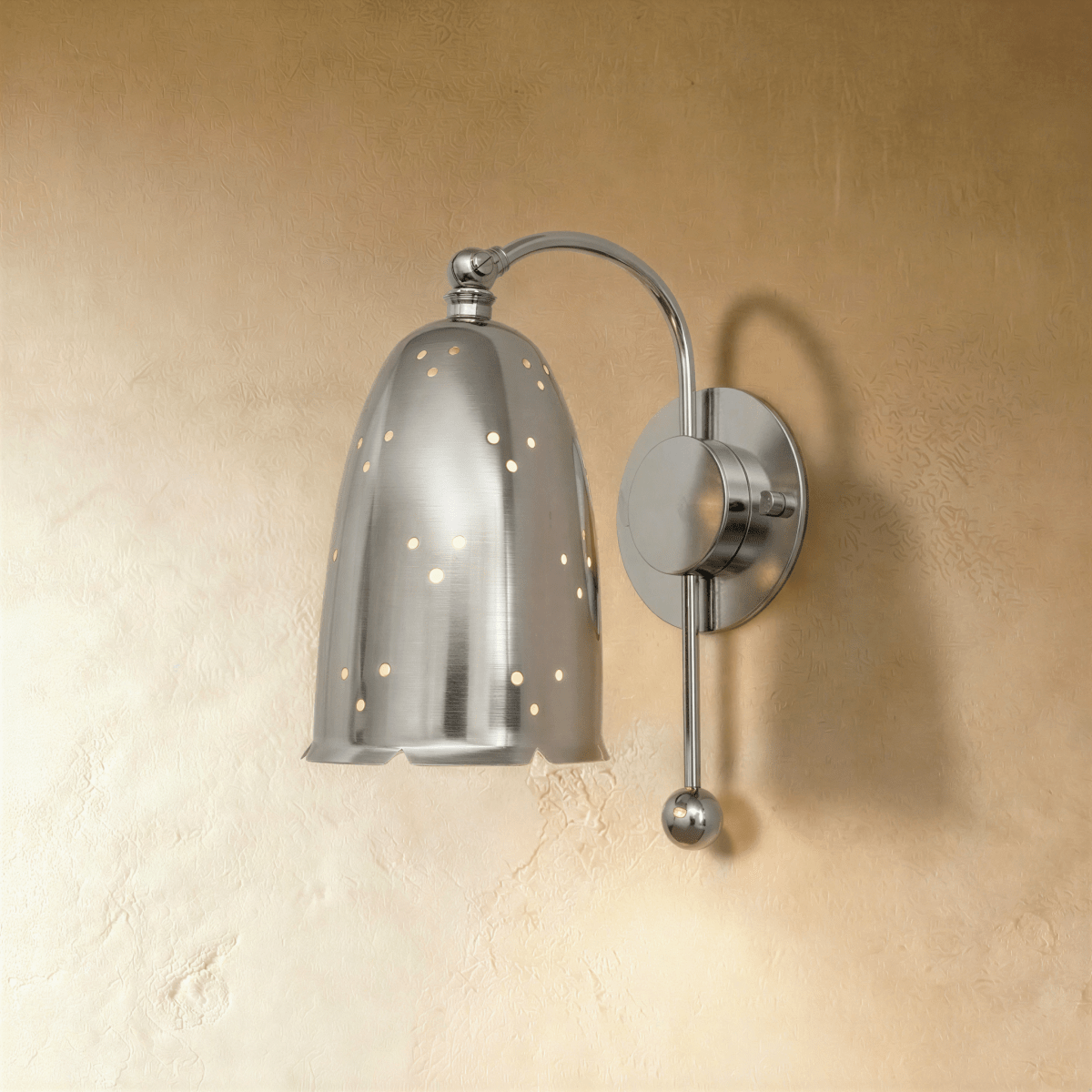 Clérachic wall lamp in chrome, its perforated bell shade suspended from a curved metal arm.