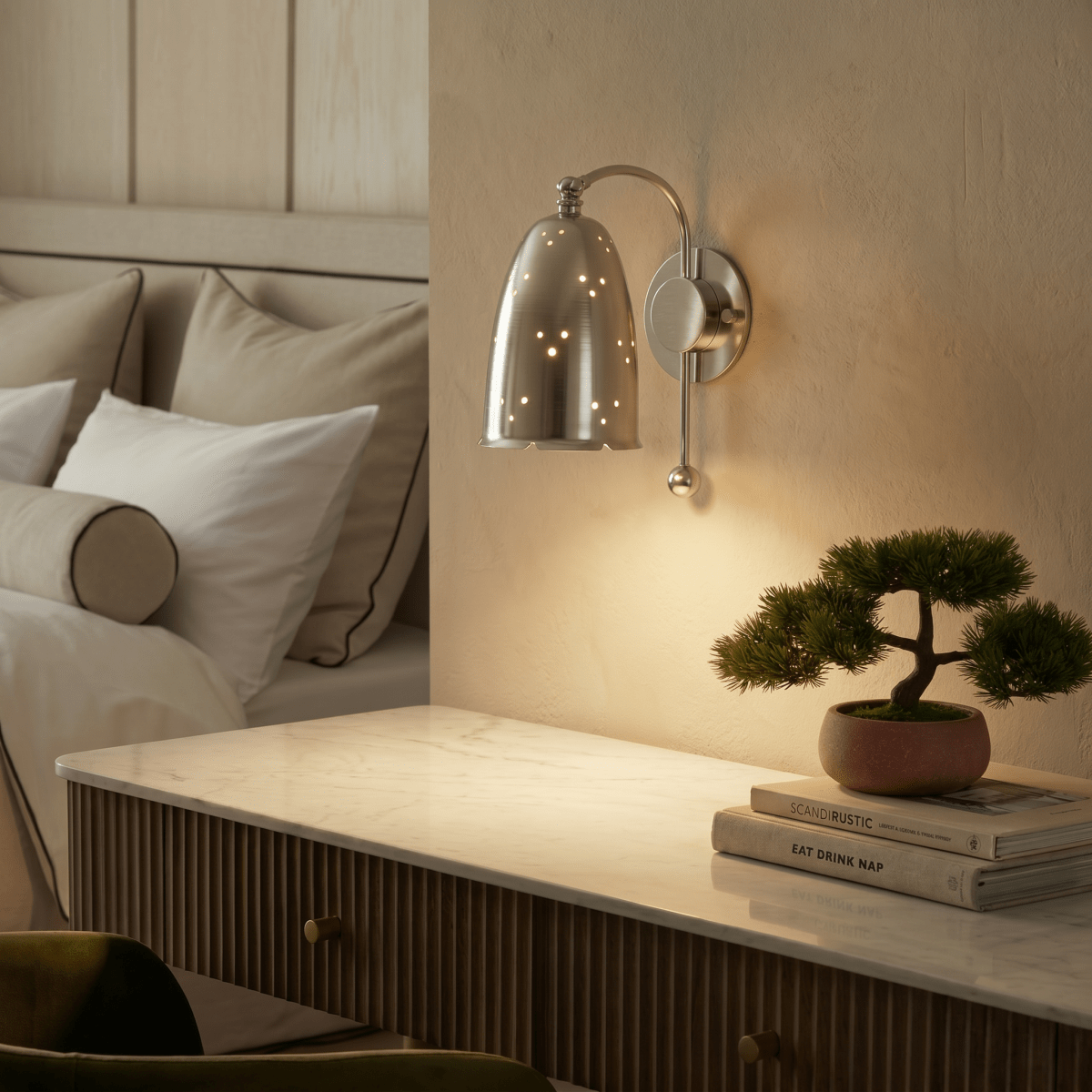 Clérachic wall lamp in chrome above a fluted dresser with a bonsai plant and stacked books.