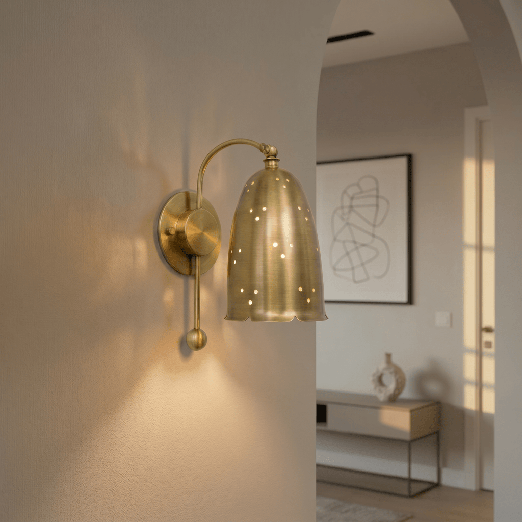 Clérachic wall lamp in brushed brass mounted by an archway leading into a bright entry hall.