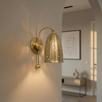 Clérachic wall lamp in brushed brass mounted by an archway leading into a bright entry hall.