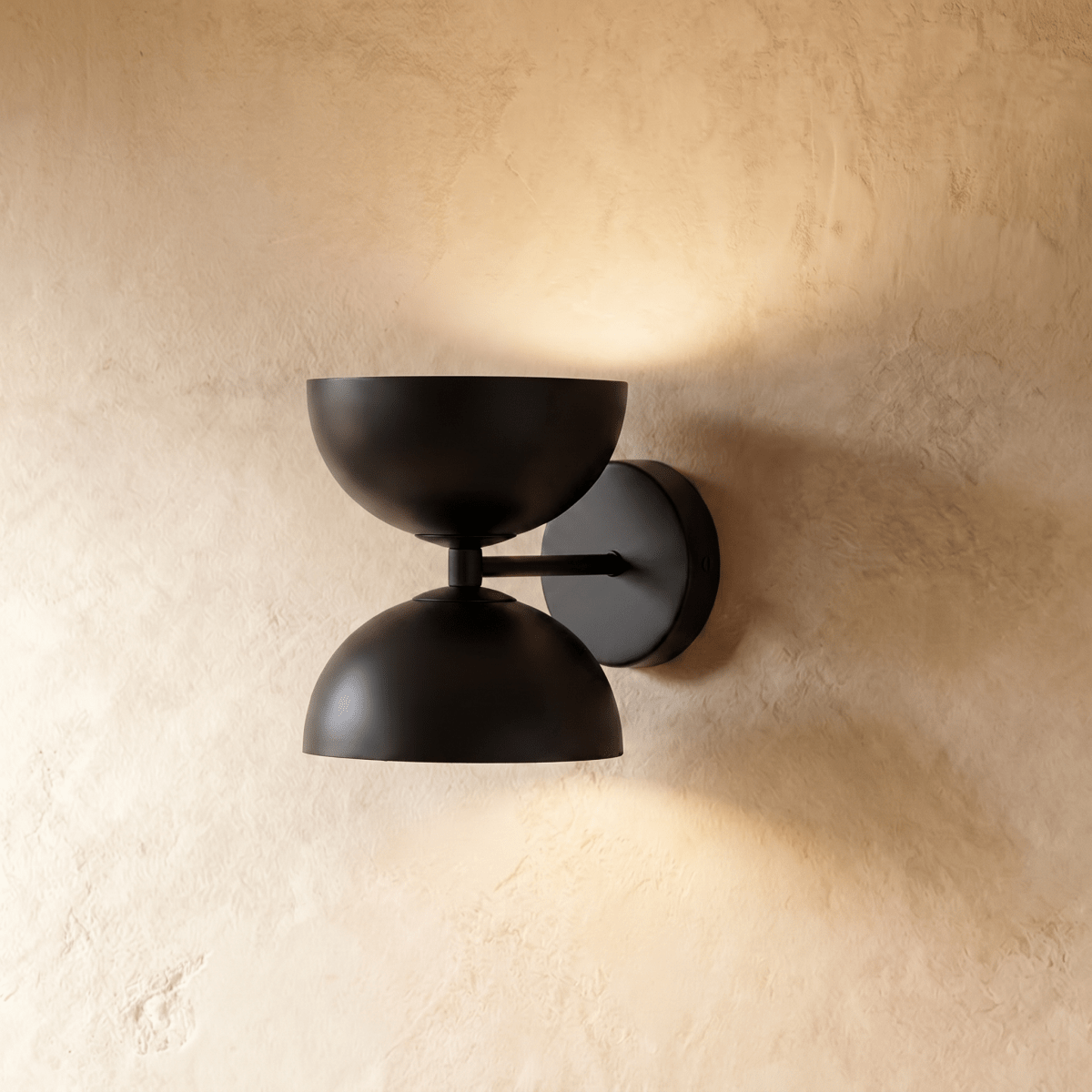 Clérachic double-dome wall sconce in matte black, mounted on a plaster wall and photographed straight-on in studio.