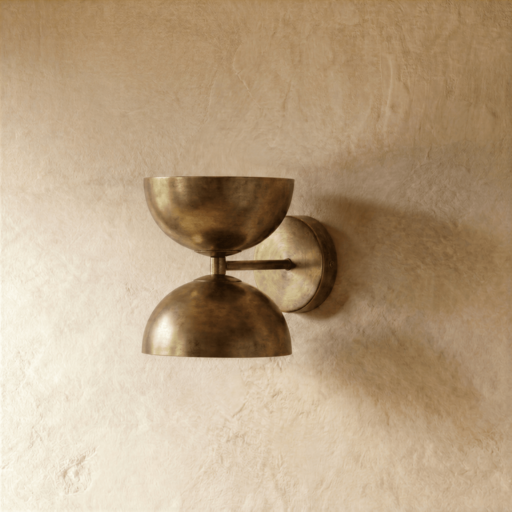 Clérachic double-dome wall sconce in vintage brass, photographed on a plain plaster wall from a slightly closer angle.