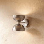 Clérachic double-dome wall sconce in brushed chrome, mounted on a plaster wall and photographed straight-on in studio.