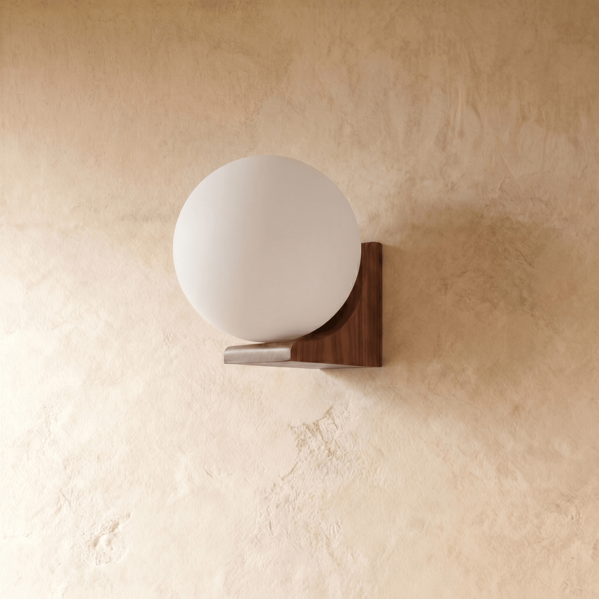 Clérachic globe wall light lit beside a bed, throwing a soft pool onto the wall