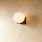 Clérachic globe wall light, opal glass sphere resting against a solid wood block