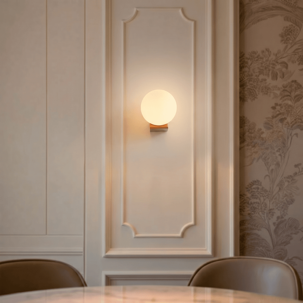 Clérachic globe wall light lit warm on a pale wall
