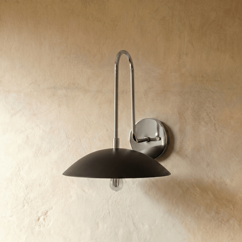 A closer view of the chrome Clérachic wall lamp, showing the join between its polished arm and black dome shade.