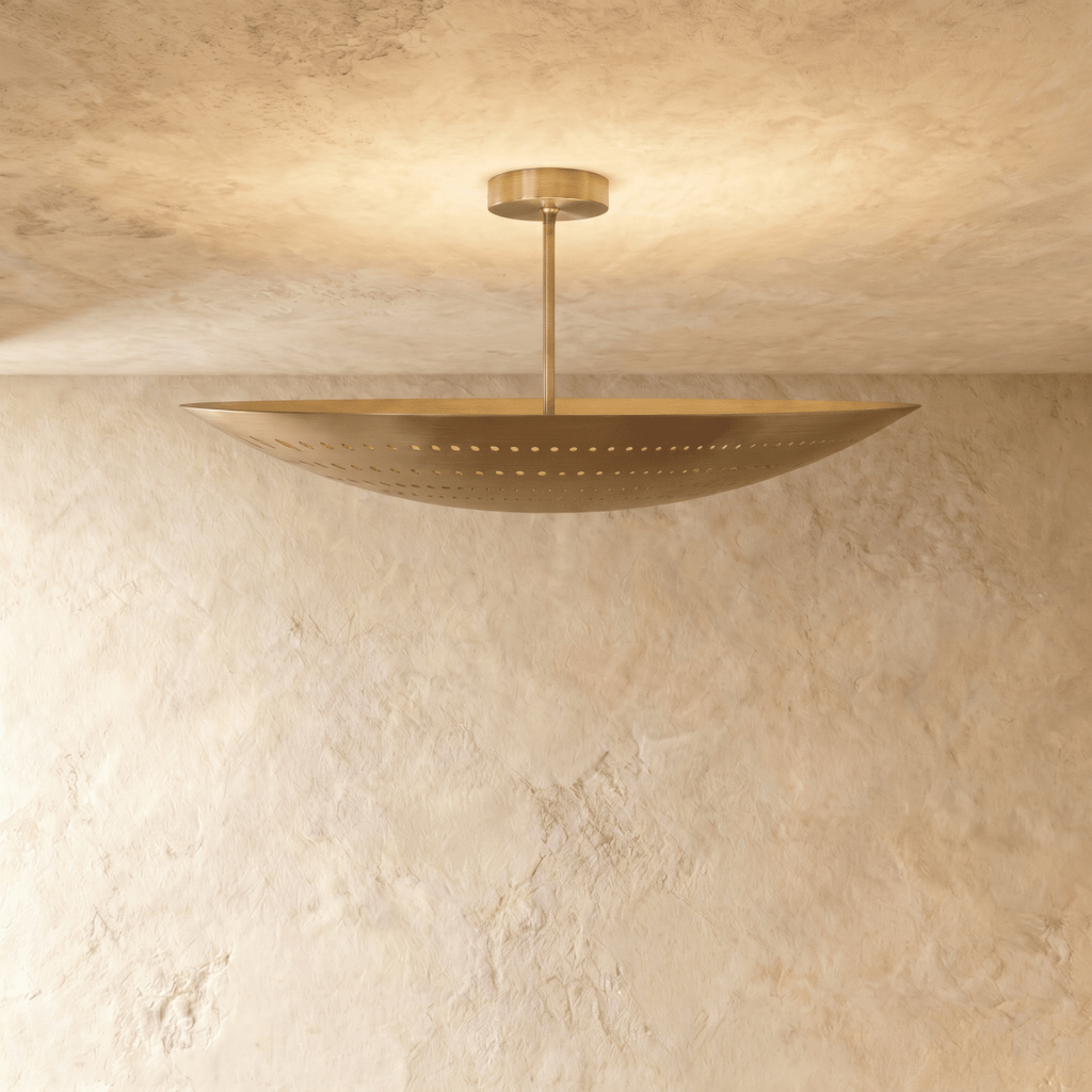 Clérachic ceiling light in a warm satin brass finish, light spilling through its pierced dot pattern.