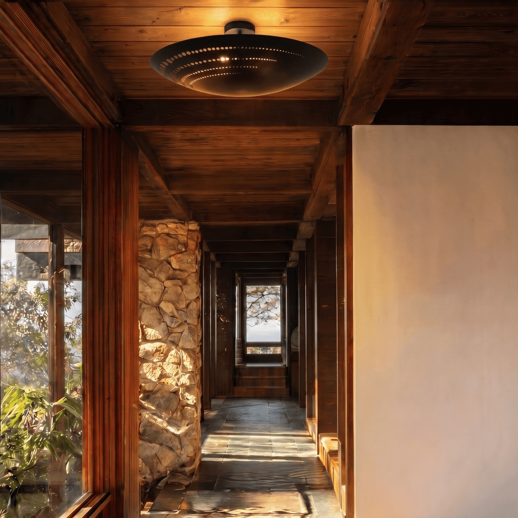 Clérachic ceiling light in matte black lighting a timber corridor beside a rough stone pillar.