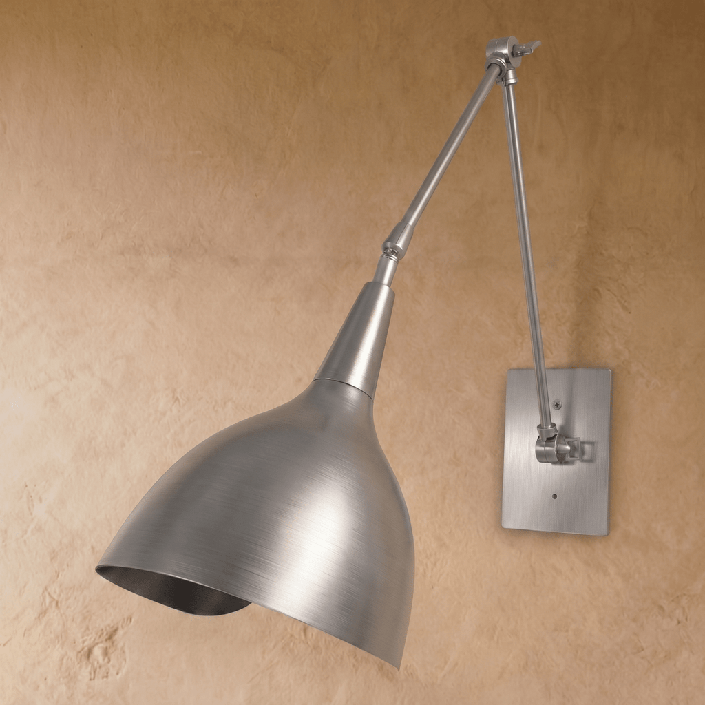 This chrome Clérachic wall lamp is shown at another angle, its jointed arm extending the cone shade forward.