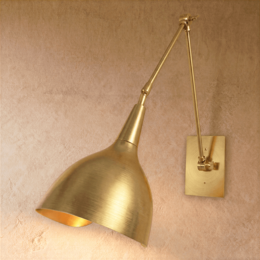Clérachic wall lamp in polished brass, its cone shade angled downward on a jointed swing arm.