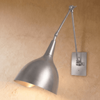 A chrome Clérachic wall lamp with a brushed cone shade on an articulated swing arm against a plaster wall.