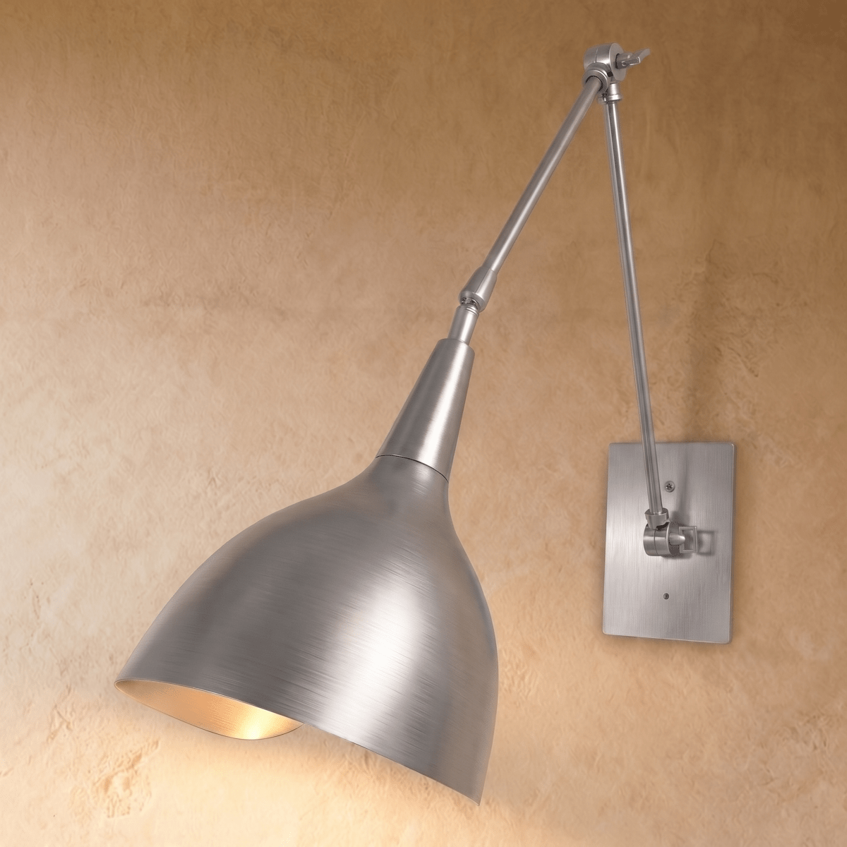 A chrome Clérachic wall lamp with a brushed cone shade on an articulated swing arm against a plaster wall.