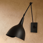 This black Clérachic wall lamp is shown from another angle, its swing arm and cone shade both matte black.