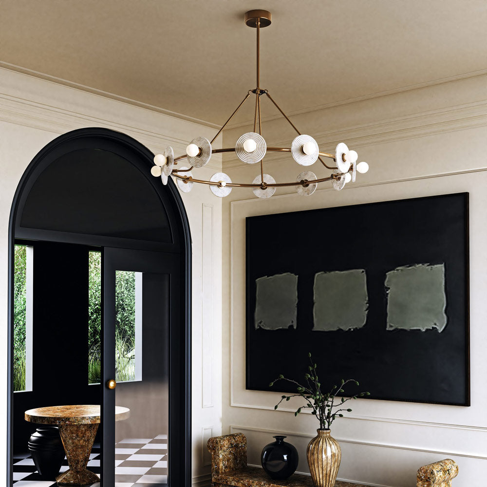 Clérachic 12-Light Alabaster Ring Chandelier lit in a pale entrance hall, beside a black arched doorway and a large dark canvas.